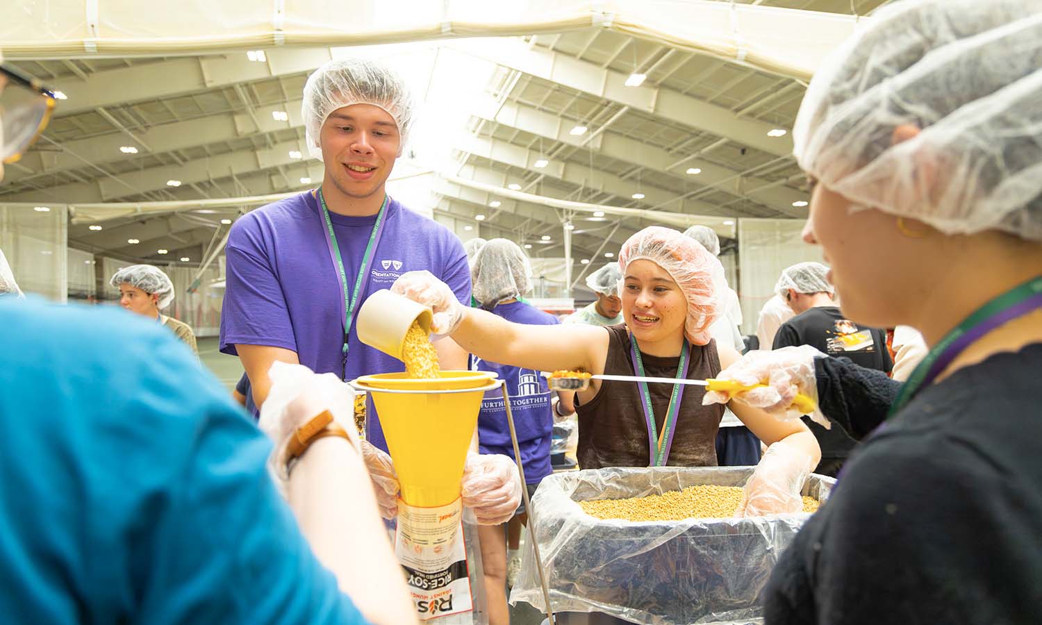 Students with hair covers pouring food into bags