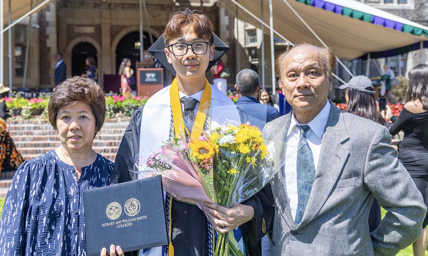 Randy Hong ’26 poses with his parents after delivering a commencement senior speech written in their honor.