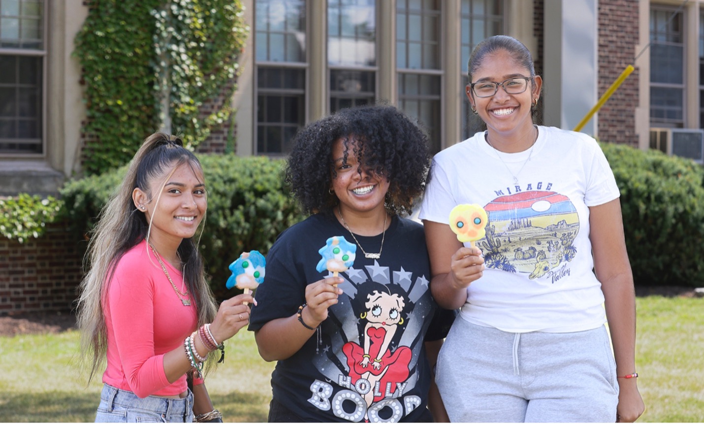 Gaitrie Singh ’26, Zulenny Reyes ’26 and Leslie Peña Almonte ’26 enjoy ice cream from a food truck on campus.