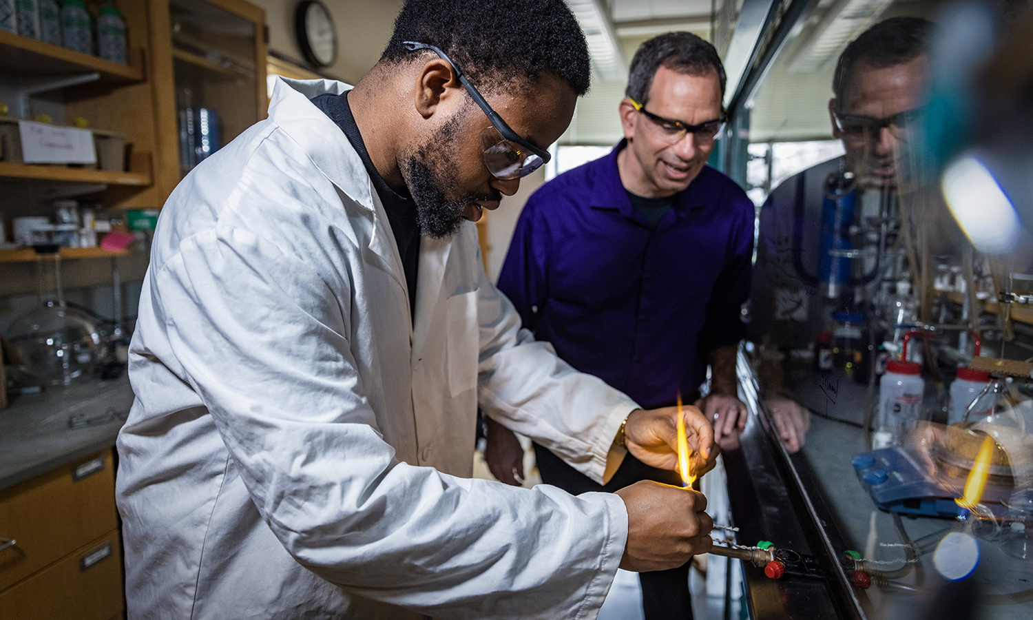 Professor of Chemistry Justin Miller looks on as Jadon Layne '25 pulls pipettes to make thin layer chromatography spotters.