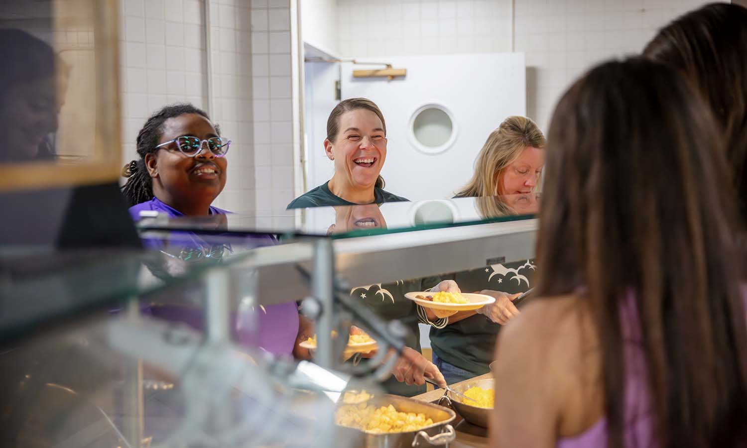 Assistant Vice President of Intercultural Affairs Renée Grant, Associate Vice President for Campus Life and Dean of Student Wellness and Support Shelle Basilio-Murray and Assistant Vice President for Campus Life Kristen Tapscott serve food at the semi-annual midnight breakfast before the beginning of finals. 