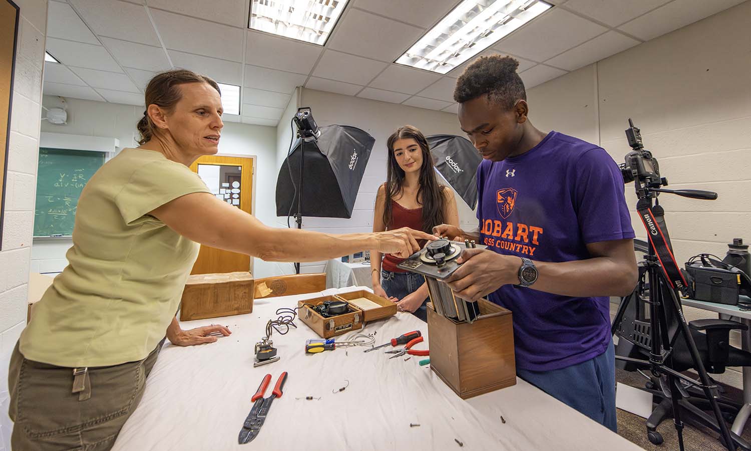 Professor of Physics Leslie Hebb, Nina Lopes ’28 and Duncan Kipkoech ’28 examine vintage equipment in Eaton Hall as part of their summer research project on the history of scientific equipment. Here, they inspect a variable inductor that was built in the late 1940s and likely used in physics laboratories at HWS during the post WWII period to build and test devices for wireless radio communication. 