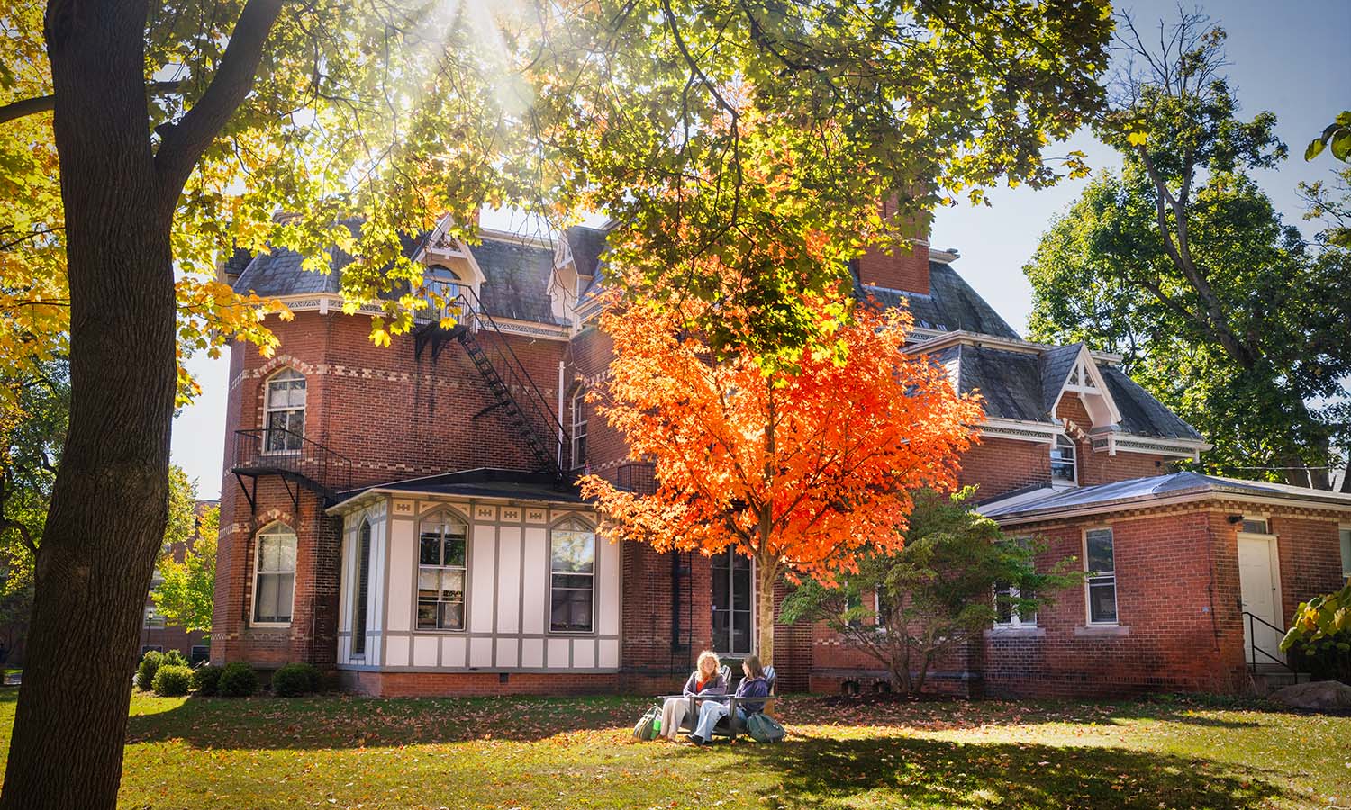 Students enjoy the fall sun behind Blackwell House on William Smith Hill.  