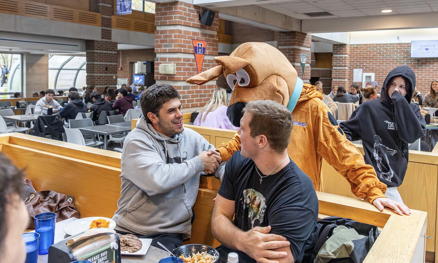 In Saga Dining Hall, President Mark D. Gearan – wearing a Scooby Doo costume for Halloween – greets members of the Hobart Football. 