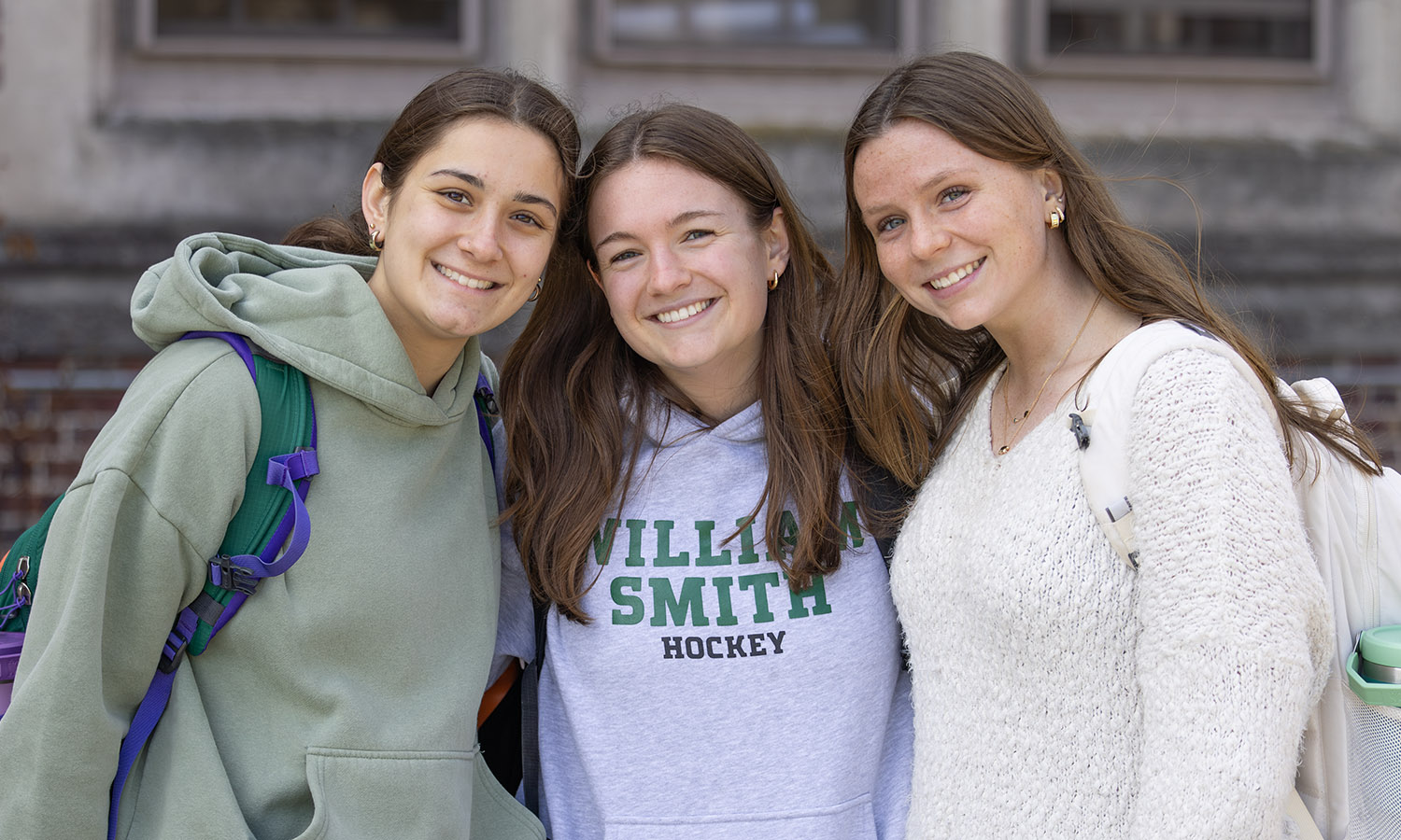 Bella Hacker ’28, Kelly Howe ’26 and Abigail Schum ’28 smile for a photo while walking to class. 