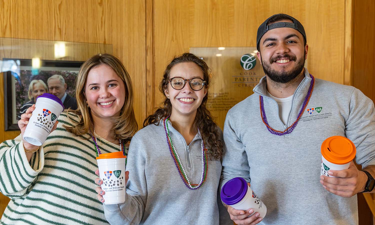 Kaleigh McPhail ’28, Abbie Ellison ’26 and Jacob Williams ’26 hand out reusable coffee cups for students to use at Finger Lakes Coffee Express in the Scandling Campus Center. 