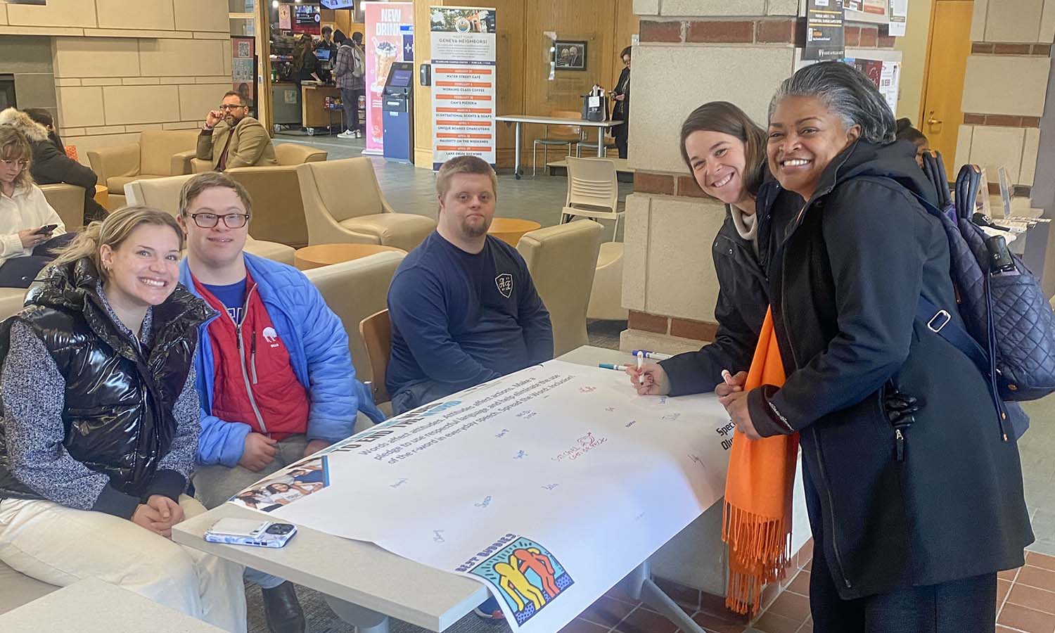 Allie Cimis ’26 and College Experience students Nic Dammen and Satchel Coende-Peck table for the annual Spread the Word Inclusion Day in Scandling Campus Center. Associate Vice President for Campus Life and Dean of Student Wellness and Support Shelle Basilio and Vice President for Diversity, Equity and Inclusion Chevanne Devaney ’95, P’21, P’23 sign the pledge to end the use of the R-word. 