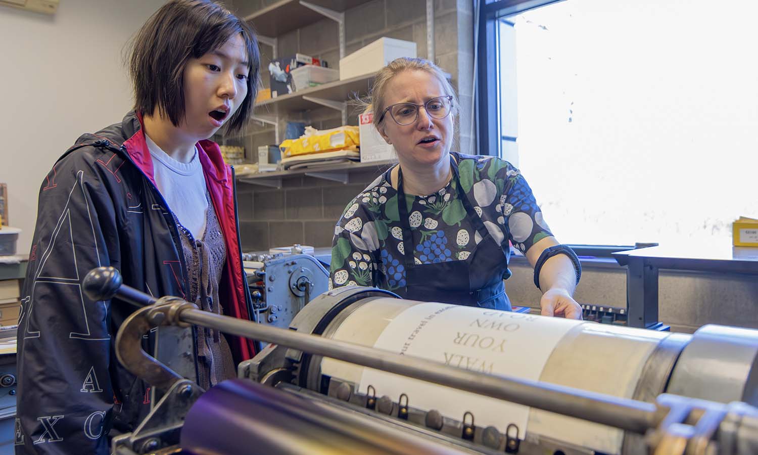 Director of the Wells Book Arts Center Mary Tasillo demonstrates how a Vandercook proof press works in the Wells Book Arts Center Maker Space. 
