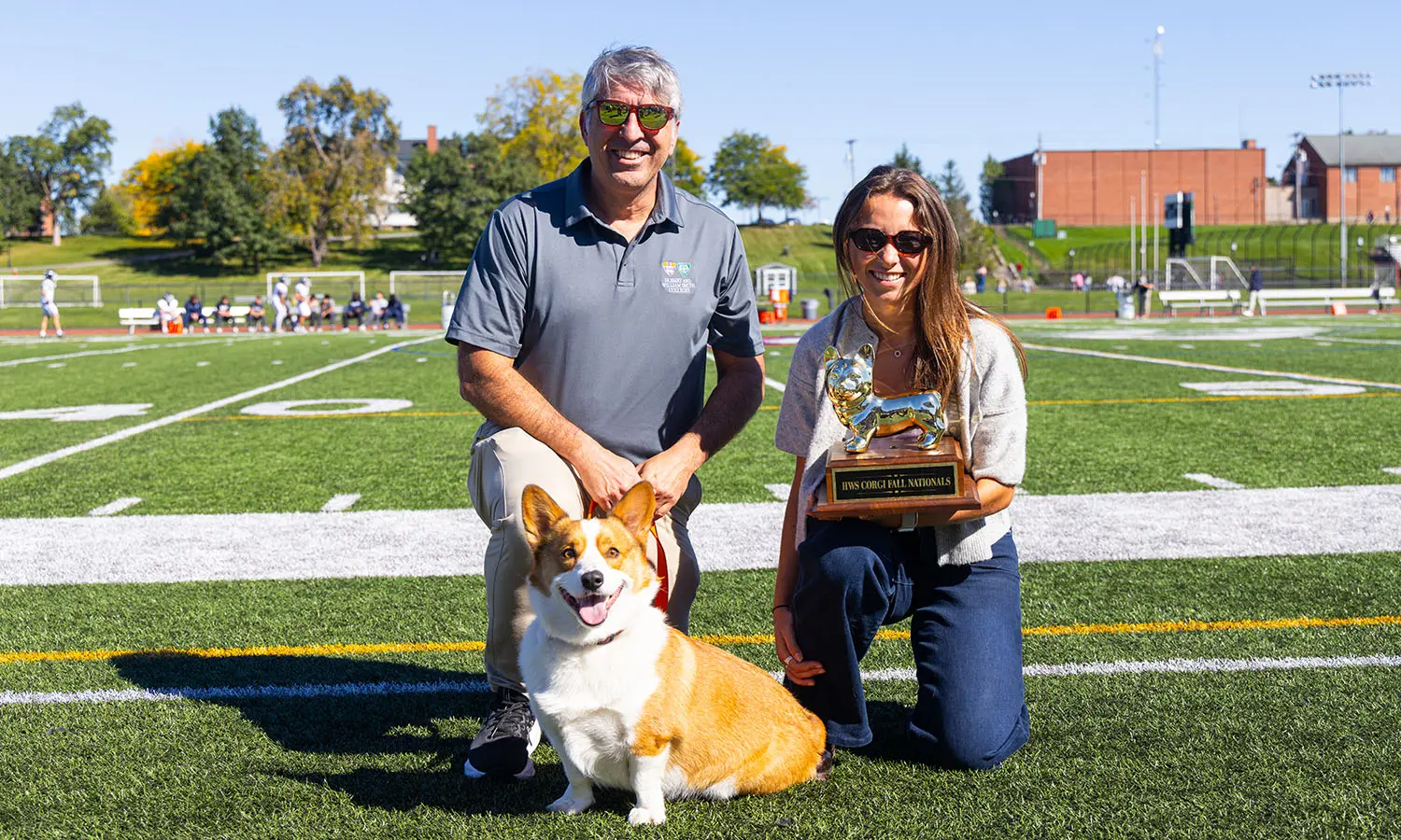Chris Ingle P ’27 and Katie Ingle '27 pose with their dog, Pablo, the winner of the annual HWS Corgi Fall Nationals race, which took place at halftime of the football game on Boswell Field. 