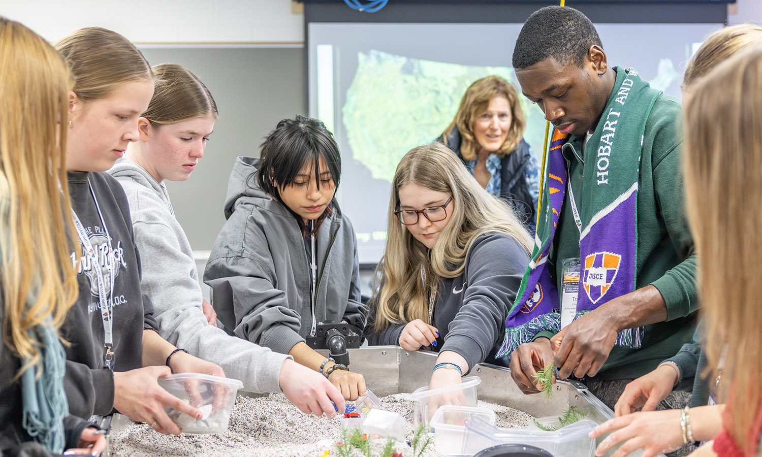 Admitted students and their families use a stream table during a sample class with Associate Professor of Geoscience David Kendrick. 
