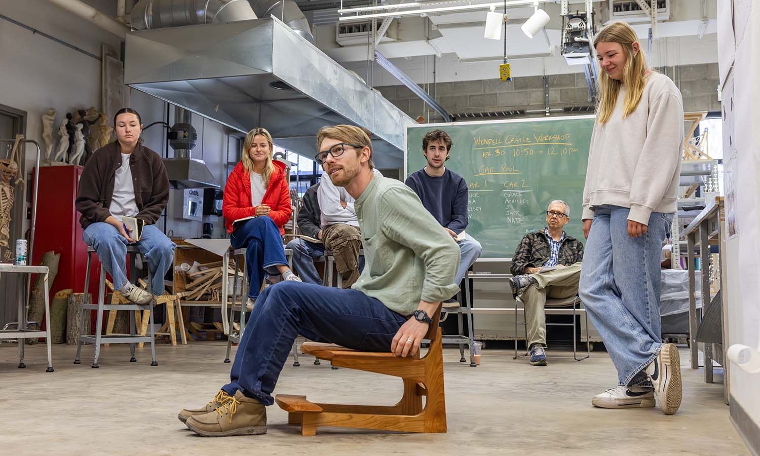 Visiting Assistant Professor of Art and Architecture Studies Patrick Kana ’12 tests the chair designed and built by Kelsey Barrows ‘26 during a final critique for “Process and Design: Furniture.”