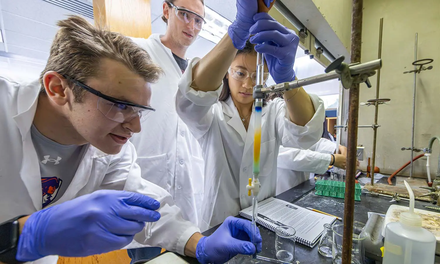 Nick Rine '29, Lily Winch '28 and Nic Humphries '29 perform column chromatography for an organic chemistry lab with Teaching Associate Professor of Chemistry David Slade. 