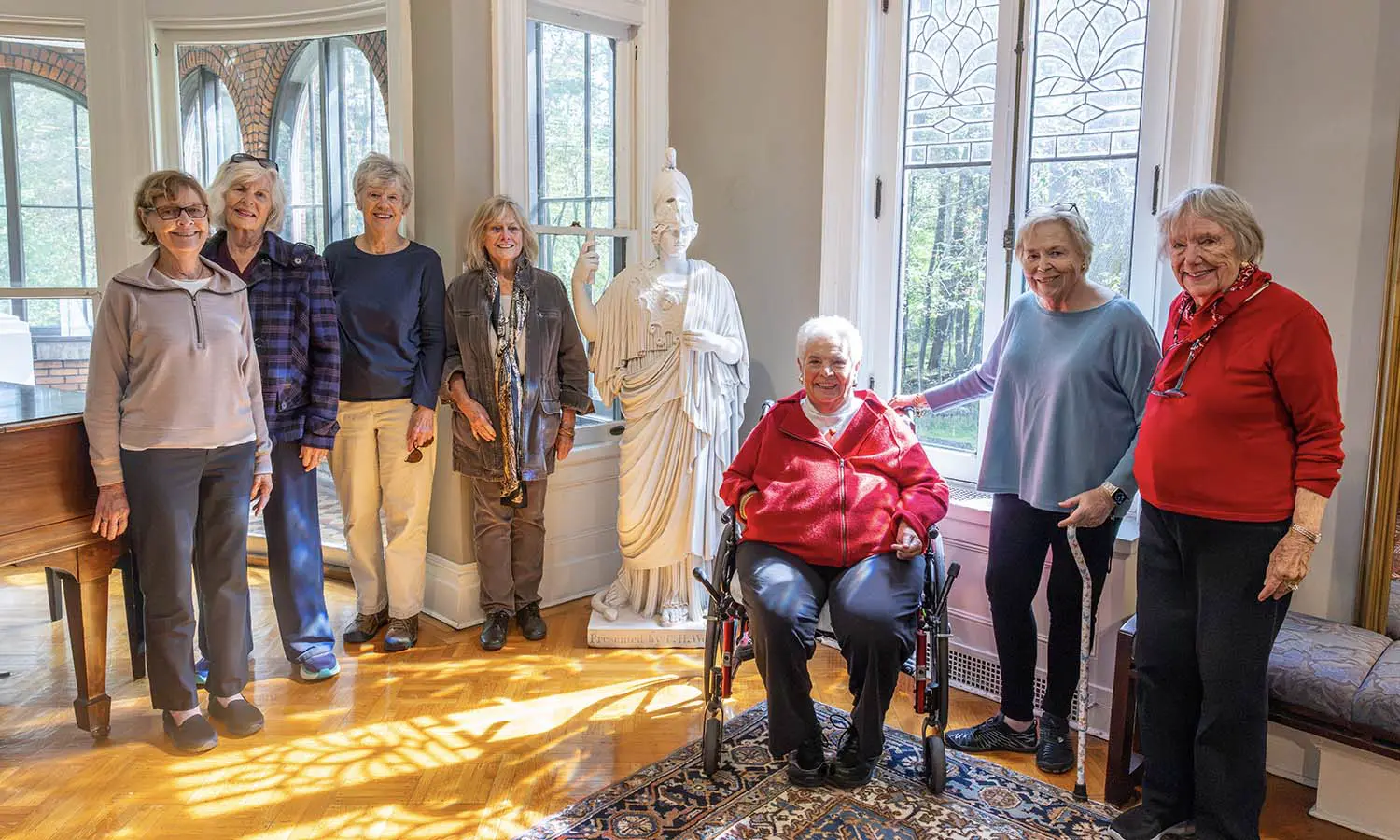 Wells College alumnae from the class of 1962 pose for a photo with the Minerva statue inside the Davis Gallery at Houghton House. 