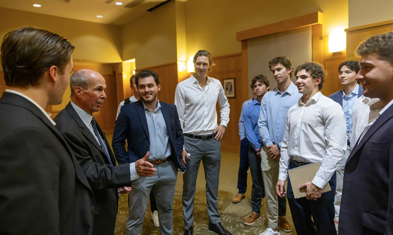 Former Trustee James F. Anderton IV ’65 speaks with members of the Hobart hockey team after the Anderton Economic Policy Symposium.  
