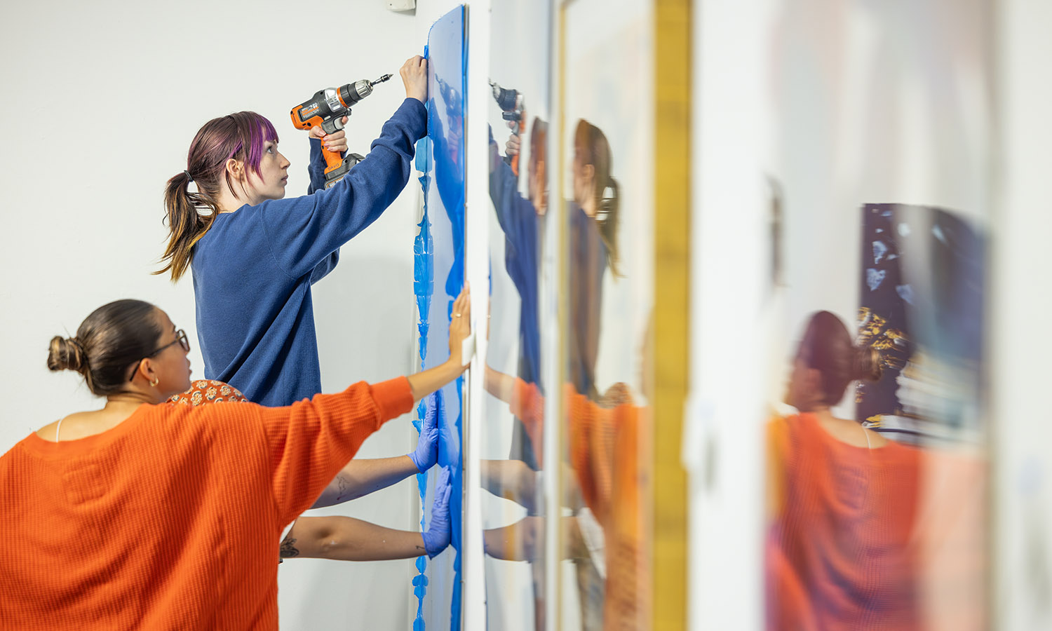Students hang artwork in the Davis Gallery in preparation for the annual faculty art exhibition. 