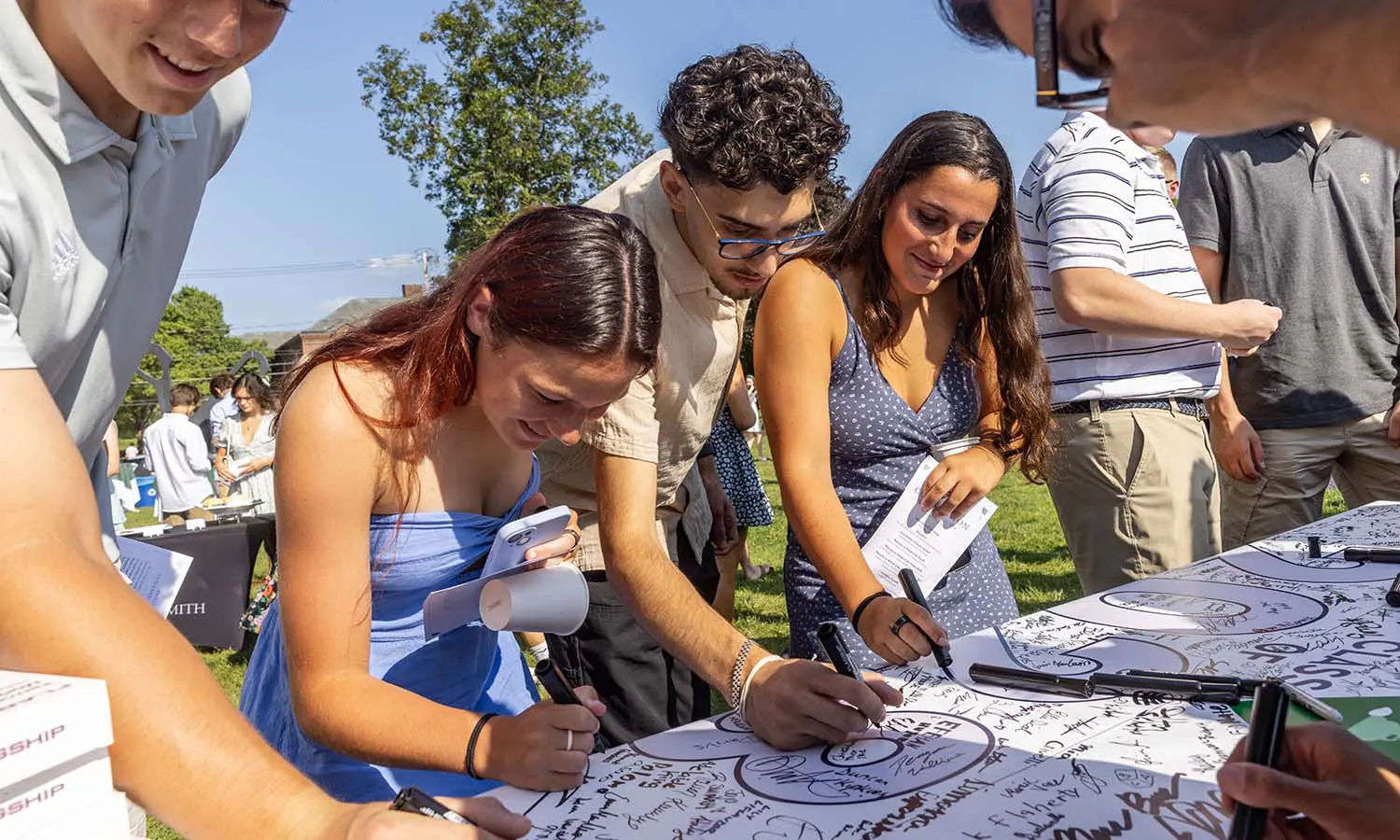 Hannah Goodness ’28, Efehan Huyuk ’28 and Fiona Gibbons ’28 sign their class banner following the Convocation ceremony.