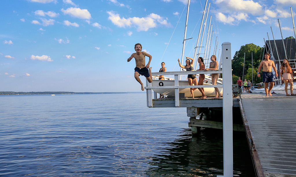 Student jumps off of the dock of the Bozzuto Boathouse
