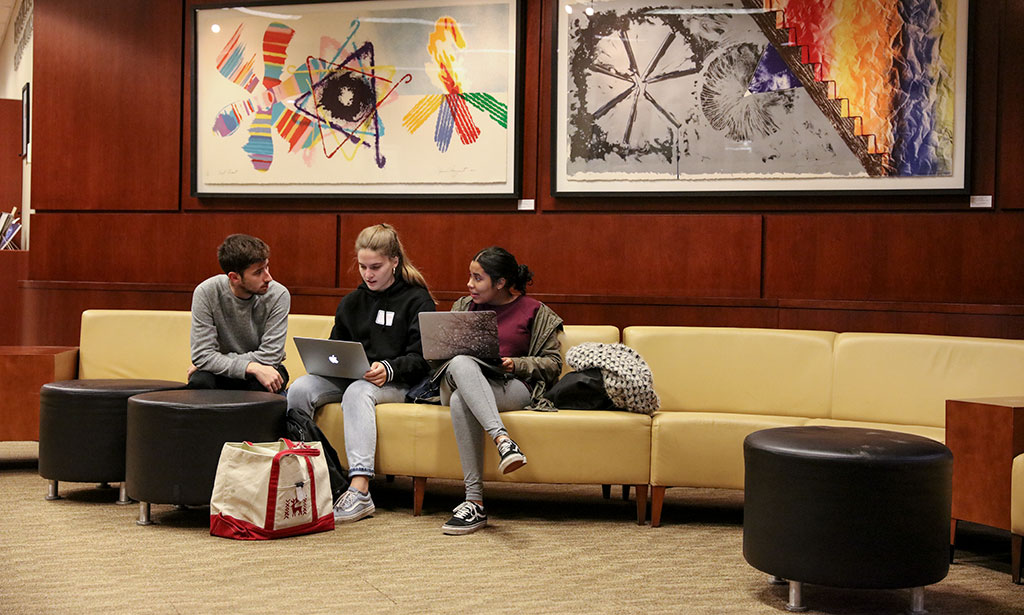 Students gather on a bench in the library