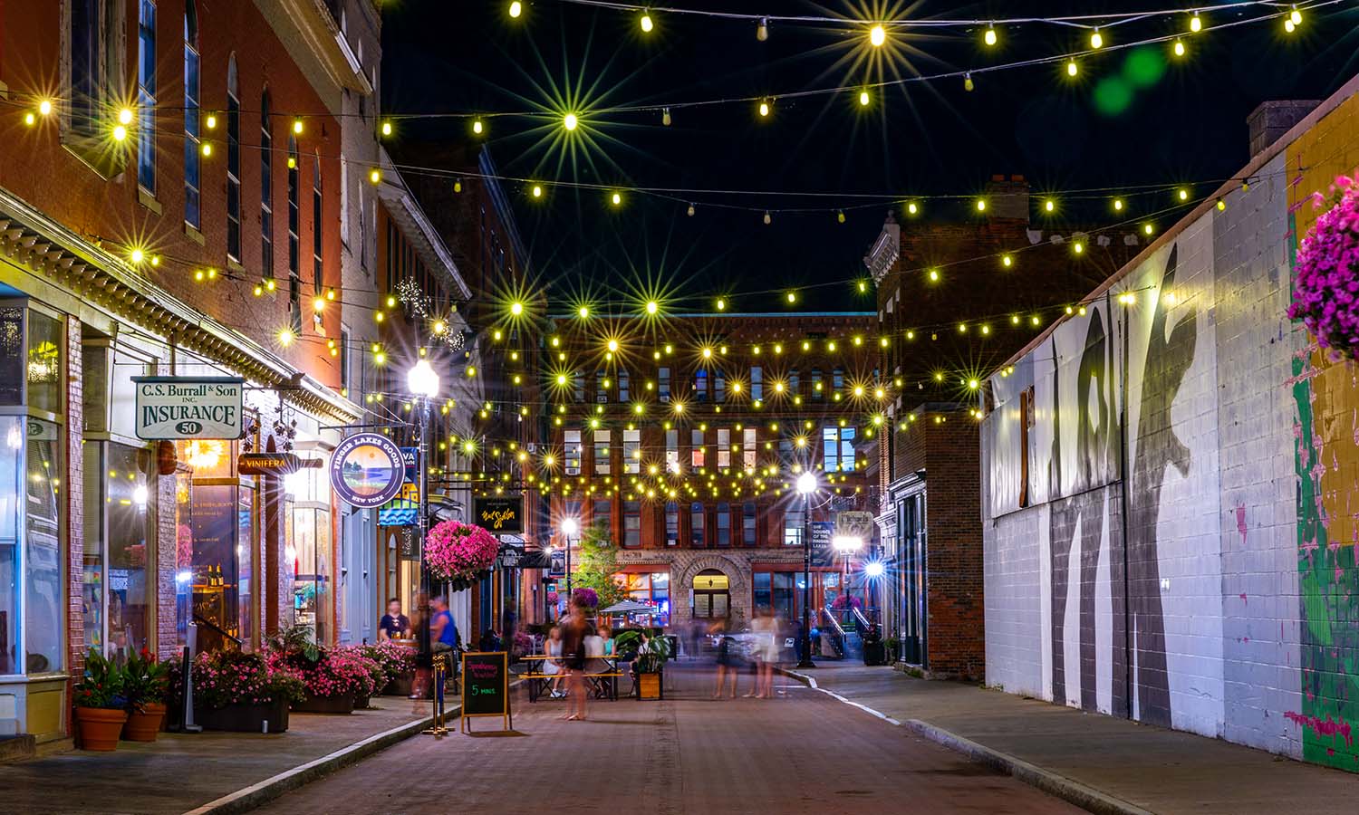 Linden Street in downtown Geneva at night, strung with cafe lights above diners at outdoor tables.
