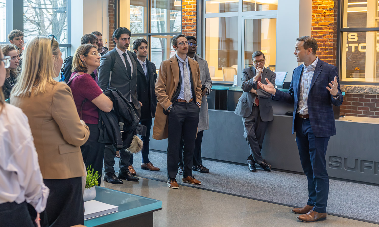 Dan Collier, Head of Red & Blue University at Suffolk Construction, welcomes students, President Mark D. Gearan and Visiting Assistant Professor of Management and Entrepreneurship Erinn Ryen to the company’s headquarters in Boston.